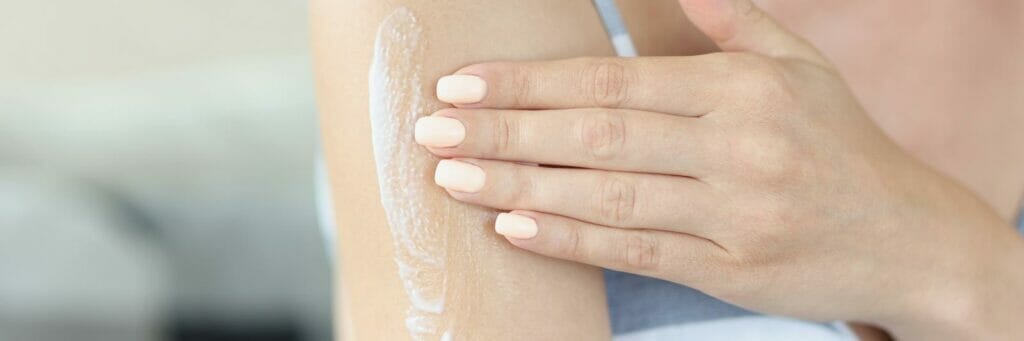 47072172 young woman applying gently moisturizing body lotion on arm